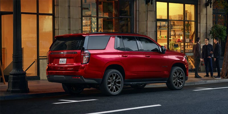 Image of a red 2024 Chevrolet Tahoe parked by a business building on a city street