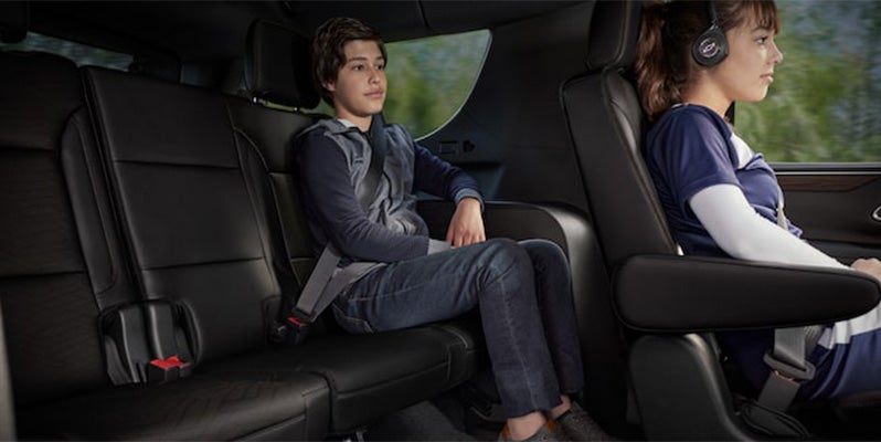 Image of the back two seating rows of the 2024 Chevrolet Tahoe's interior, with two children sitting one behind the other on each row