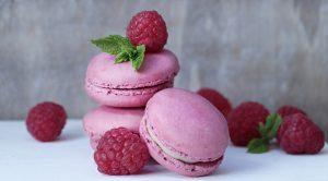 Raspberry macaroons and fresh raspberries stacked on a white counter. | St. Louis, MO
