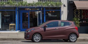 A dark blush 2021 Chevrolet Spark parked on the curb in front of a restaurant. | Chevrolet dealer in St. Louis, MO