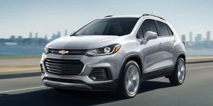 A silver 2021 Chevrolet Trax being driven on the highway with buildings far off in the background. | Chevrolet dealer in St. Louis, MO